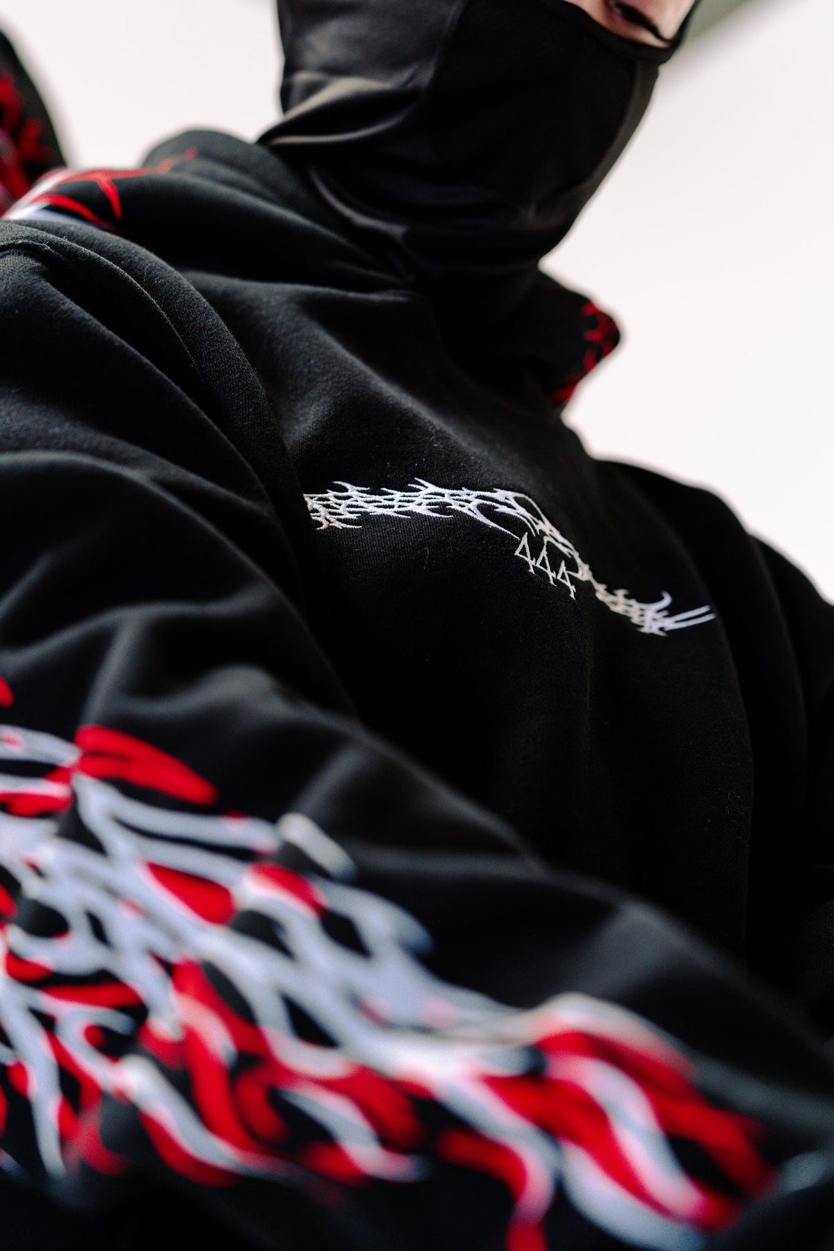Black reflective hoodie with red tribal back graphic, worn by rider